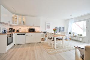 a kitchen with white cabinets and a wooden table at Küstenkinder Whg 17 in Kellenhusen