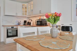 a kitchen with a table with flowers in a vase at Küstenkinder Whg 17 in Kellenhusen