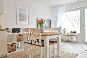 a white kitchen with a wooden table and chairs at Küstenkinder Whg 17 in Kellenhusen