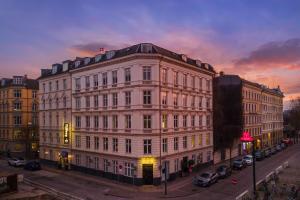 ein großes weißes Gebäude an einer Stadtstraße bei Sonnenuntergang in der Unterkunft Hotel Tiffany in Kopenhagen