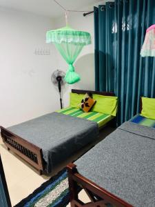 two beds in a room with blue curtains at PINI ROO Villa in Badulla