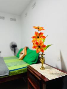 a vase with flowers on a table next to a bed at PINI ROO Villa in Badulla +15 photos