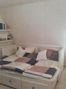 a bed with a checkered blanket and pillows on it at Abenteuerurlaub im Tannenwald in Ilmenau