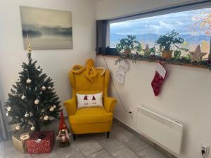 a living room with a christmas tree and a yellow chair at Antracit House in Kismaros +1 photo