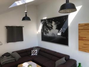 a living room with a brown couch and two hanging lights at Antracit House in Kismaros