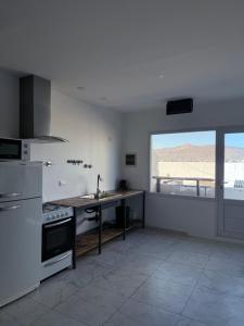 a kitchen with white appliances and a large window at Softi Sur in Comodoro Rivadavia +10 photos