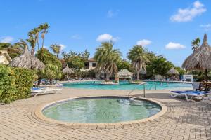 a pool at a resort with chairs and palm trees at Dushi Boho in Willemstad