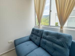 a blue couch sitting in front of a window at Fee4Me Flat near Neomundo in Bucaramanga