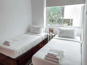 two beds in a room with a window at Fee4Me Flat near Neomundo in Bucaramanga