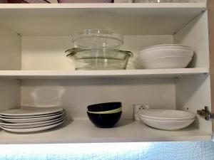 a shelf filled with dishes and bowls and plates at Unique main square apartment - AC - Balcony - Coffee Machine - Washer - Kitchen- Parking available Free public or Paid Private for 20 euro per stay Please read our emails in Poprad +30 photos