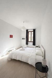 a white bedroom with a large white bed and a table at Casa Ventuno in Civitavecchia