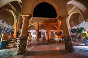 a room with arches and tables in a building at Riad Nkob in Nkob