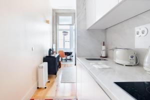 a kitchen with a white counter top and a table at Get a Golden and Flower Flat in Porto