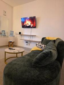 a living room with a couch and a tv on the wall at Misty Cabins in Ruringʼu