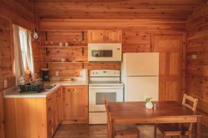 a kitchen with a stove and a refrigerator and a table at Lawrencetown Lodge - The Maple Studio in Three Fathom Harbour +10 photos