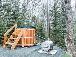 a large wooden tub sitting next to a tree at Lawrencetown Lodge - The Maple Studio in Three Fathom Harbour