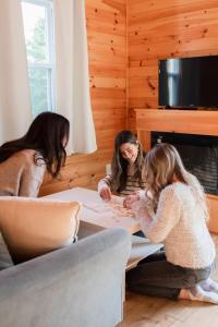 two women sitting at a table writing on a piece of paper at Lawrencetown Lodge - The Maple Studio in Three Fathom Harbour