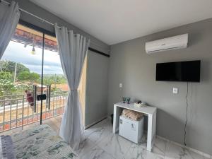 a room with a tv and a window with a balcony at Pousada Buganvília in Tianguá