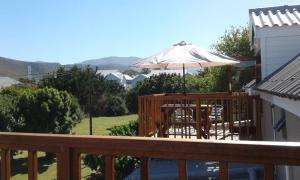 a deck with a table and an umbrella at The Mayflower in Hermanus