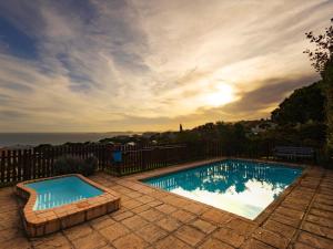 a swimming pool with a sunset in the background at Waves & Whales in Brenton-on-Sea