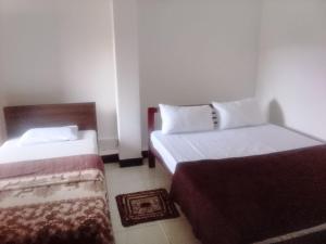 a room with two beds and a chair in it at Ambewela Pattipola snowflak rest in Nuwara Eliya