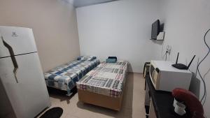 a small room with two beds and a refrigerator at Casa kitnet in São Caetano do Sul