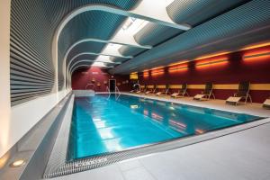 a large swimming pool in a building with chairs at Mirabeau Etoile in Zermatt