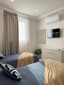 a bedroom with two beds and a flat screen tv at Spielberg - Garage, Outdoor Area, Close to Beach in Marsaskala