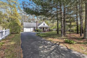 a driveway leading to a white house with trees at Jenkins Pond Beach Access with BBall Hoop & Grill, Bright Cape Cod Retreat near Jenkins Pond in Falmouth - Parking, Modern Retreat with Outdoor Space, 24 Hour Hospitality in Falmouth +22 photos
