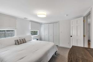 a white bedroom with a bed and a window at Jenkins Pond Beach Access with BBall Hoop & Grill, Bright Cape Cod Retreat near Jenkins Pond in Falmouth - Parking, Modern Retreat with Outdoor Space, 24 Hour Hospitality in Falmouth