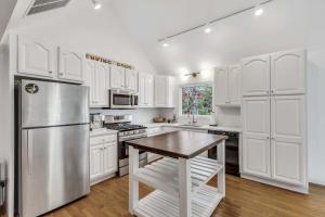 a kitchen with white cabinets and a stainless steel refrigerator at Jenkins Pond Beach Access with BBall Hoop & Grill, Bright Cape Cod Retreat near Jenkins Pond in Falmouth - Parking, Modern Retreat with Outdoor Space, 24 Hour Hospitality in Falmouth