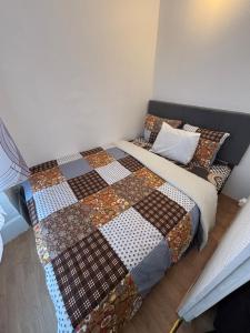 a bedroom with a bed with a quilt on it at Super appartement in Malesherbes