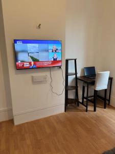 a flat screen tv on a wall with a table and a laptop at Super appartement in Malesherbes
