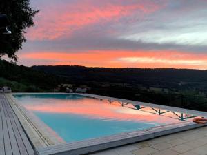 a large swimming pool with a sunset in the background at Agriturismo Tenuta Lapone in Orvieto