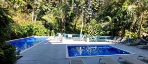 a swimming pool with lounge chairs and a swimming pool at Hotel Plaza Yara in Manuel Antonio