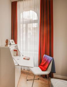 a white desk and a chair in front of a window at Amalienhof Serviced Apartments in Weimar
