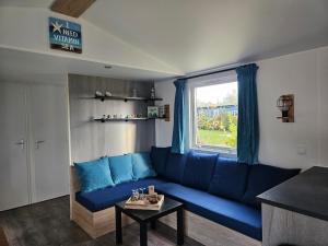 a blue couch in a living room with a window at Chalet First Stage - Renesse in Renesse