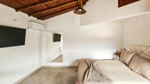 a bedroom with a bed and a tv on the wall at Saíra Chalés in Lençóis