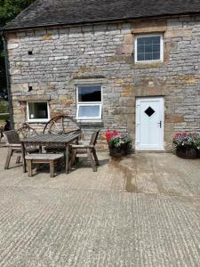 a stone building with a table and benches in front of it at Crowtrees Barns in Waterhouses