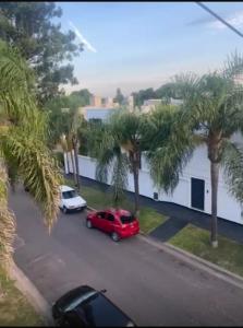 a red car parked in a parking lot with palm trees at El Remanso de Paracao in Paraná