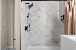 a bathroom with a shower with white marble tiles at Blatchley Rooms by Yale in New Haven