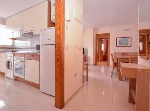 a kitchen with a white refrigerator and a table at APCOSTAS Pereda Mar - Familiar in Puerto de Gandía