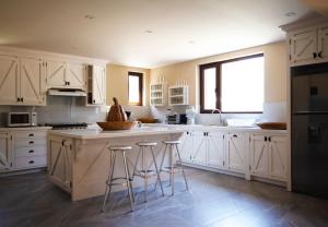 a kitchen with white cabinets and a island with bar stools at Villa Ecuestre in Cedro