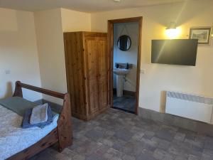 a bedroom with a bed and a television on the wall at Crowtrees Barns in Waterhouses