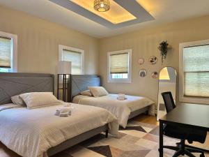 a bedroom with two beds and a desk and windows at Blatchley Rooms by Yale in New Haven