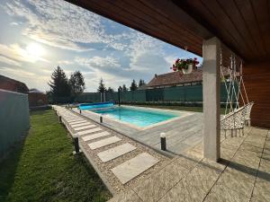a swimming pool in a yard next to a house at Somogyi Apartman Natur in Ciucsîngeorgiu
