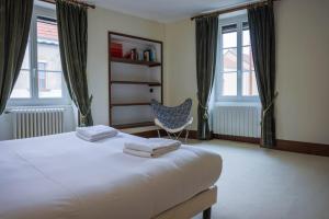 a bedroom with a bed and a chair and windows at L'Ancien Relais in Genouilly