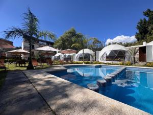 a swimming pool with chairs and umbrellas in a resort at Glamping en Valle de Bravo in Valle de Bravo +52 photos