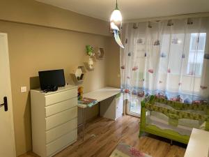 a bedroom with a crib and a dresser with a desk at Luxurious flat - Pleven center in Pleven
