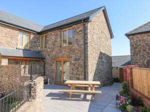 a wooden picnic table in front of a brick building at Grange Cottage in Crediton